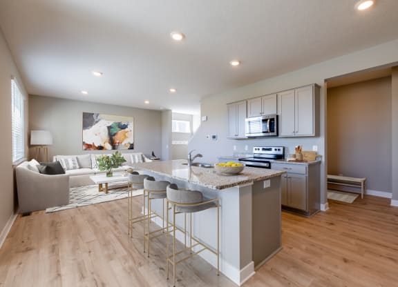 an open kitchen and living room with a marble counter top