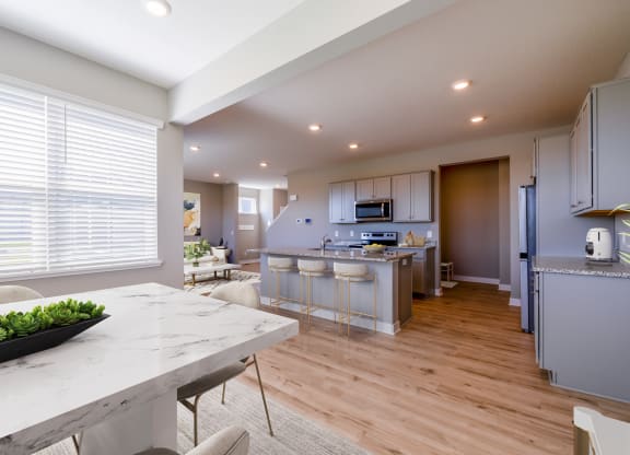 an open kitchen and dining room with a marble counter top and a table with chairs