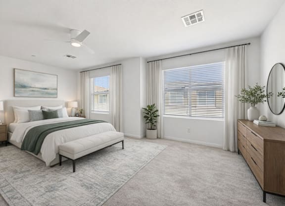 A well-lit bedroom with a large bed, a side table, and a dresser.