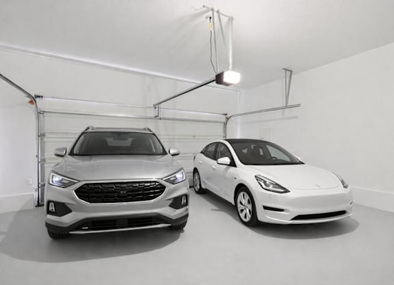 Two cars are parked in a white-walled garage.