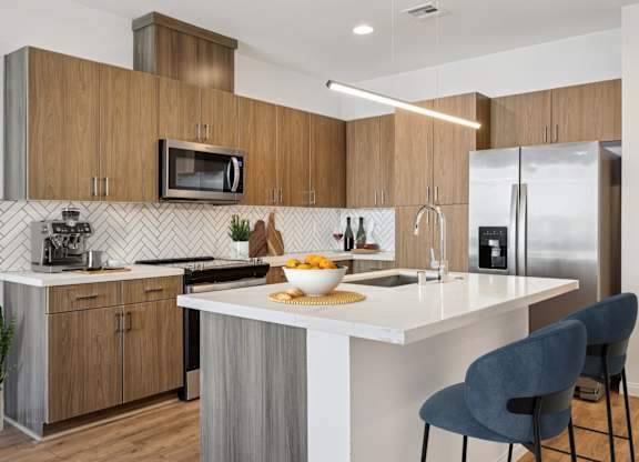 A modern kitchen with a white countertop and wooden cabinets.