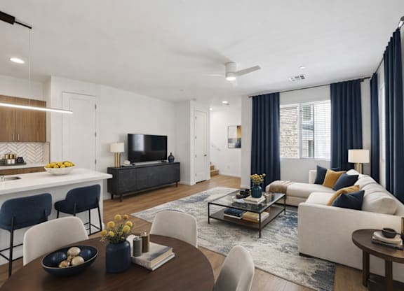 A modern living room with a white sofa, a wooden coffee table, and a dark-colored television.