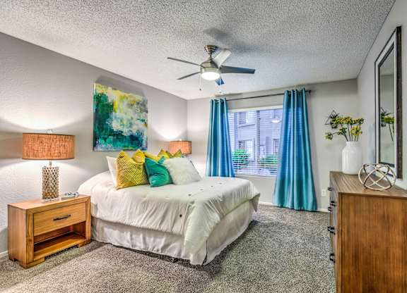 A bedroom with a bed, nightstand, and a painting on the wall.