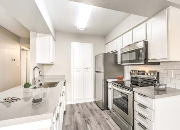 A modern kitchen with stainless steel appliances and white cabinetry.