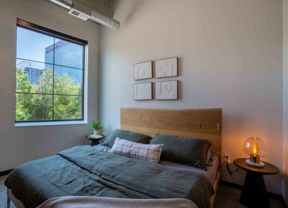 Bloomington, MN Apartments - Carbon31 - Bedroom with Large Window, Wall-to-wall Carpet, Large Bed, and Circular Nightstand