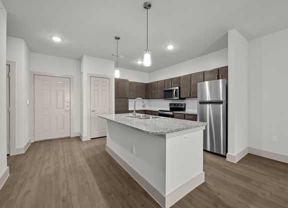 an empty kitchen with a marble counter top and a stainless steel refrigerator