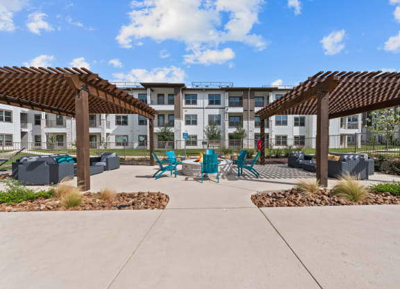 a patio with chairs and umbrellas in front of an apartment building