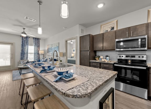 an open kitchen and dining area with a granite counter top and stainless steel appliances