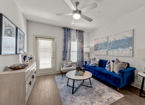 a living room with a blue couch and a ceiling fan