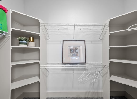 a walk in closet with white shelves and a picture on the wall