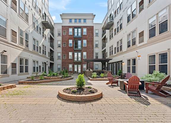 A courtyard with a brick circle in the middle and a red bench on the right.