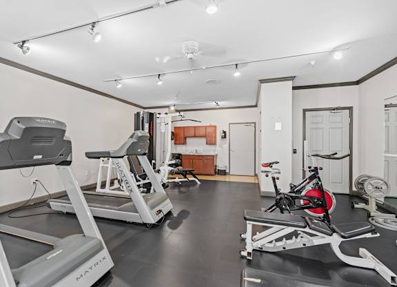 A gym with treadmills, a stationary bike, and a weight bench.