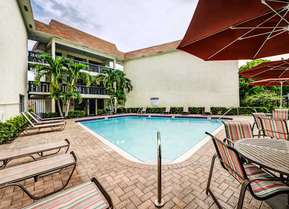 Sparkling pool with shaded seating at Coronado Springs Apartments in Palm Springs, FL. Pet-friendly community featuring resort-style amenities.