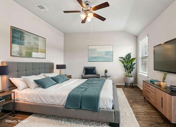 A bedroom with a bed, a ceiling fan, and a television.