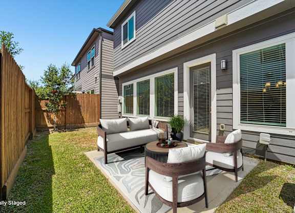 A patio with a table and chairs is in front of a house.