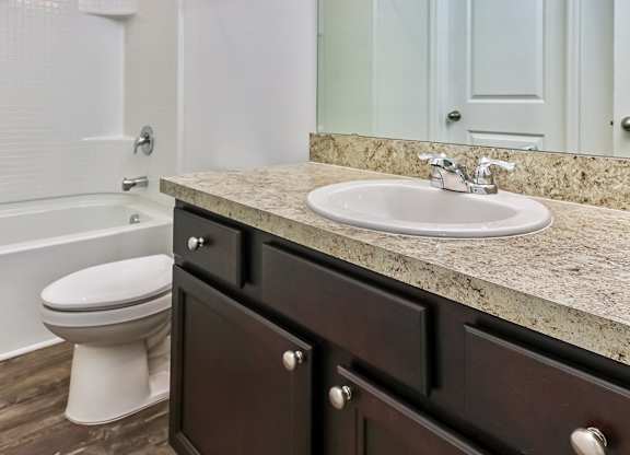 A bathroom with a white toilet and a marble countertop.