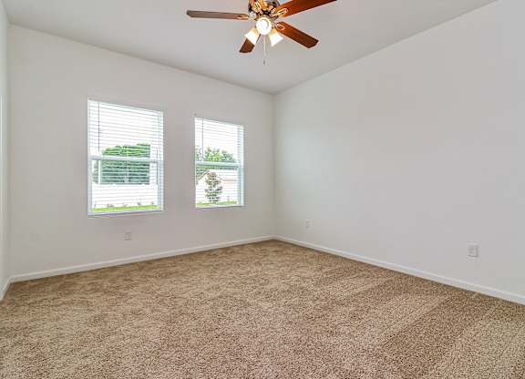 A room with a ceiling fan and carpeted floor.