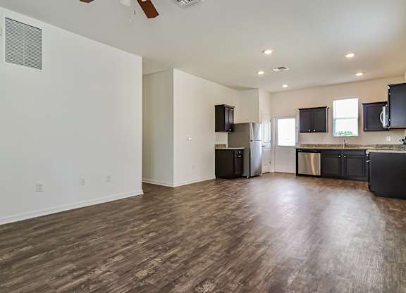 A spacious kitchen with dark wood floors and modern appliances.