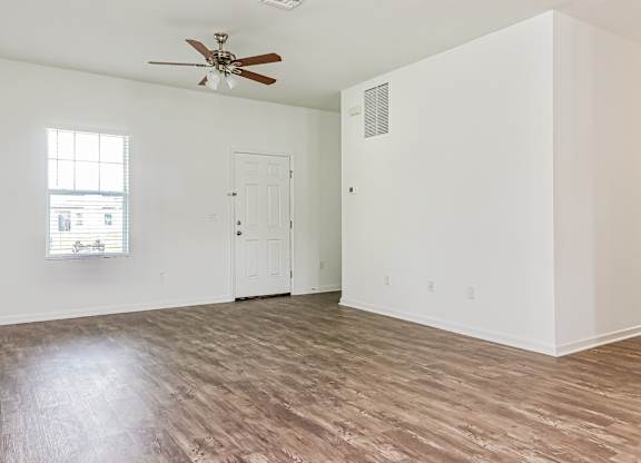 A room with a ceiling fan and a window with blinds.