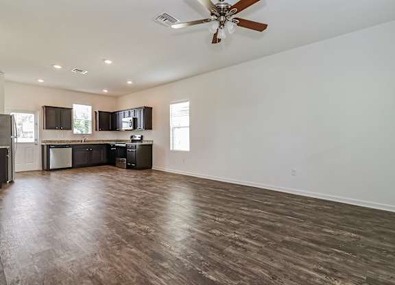 A spacious room with a ceiling fan and wooden flooring.