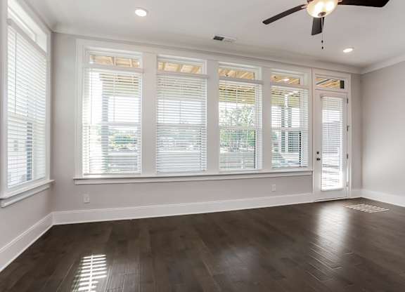 A room with a ceiling fan and wooden flooring.