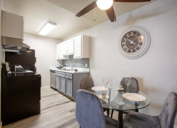 Apartments for Rent in Tucson, AZ - Peaks at Redington - Dining Area with Wood-Style Flooring, Glass-Top Table, Chairs, Ceiling Fan, and View of Kitchen.