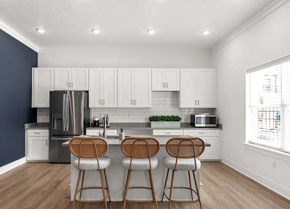 A kitchen with white cabinets and a stainless steel refrigerator.