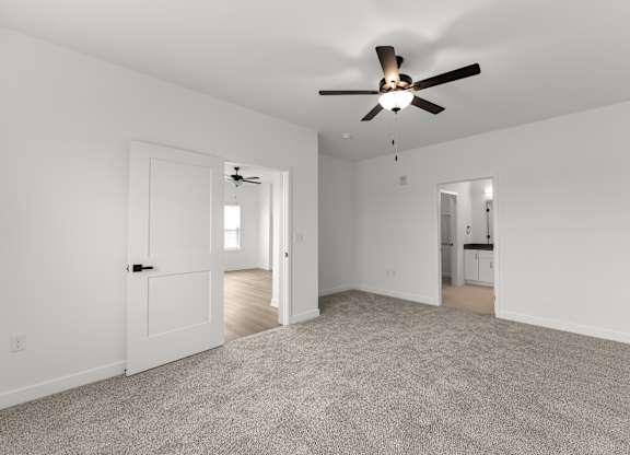A spacious room with a ceiling fan and carpeted floor.