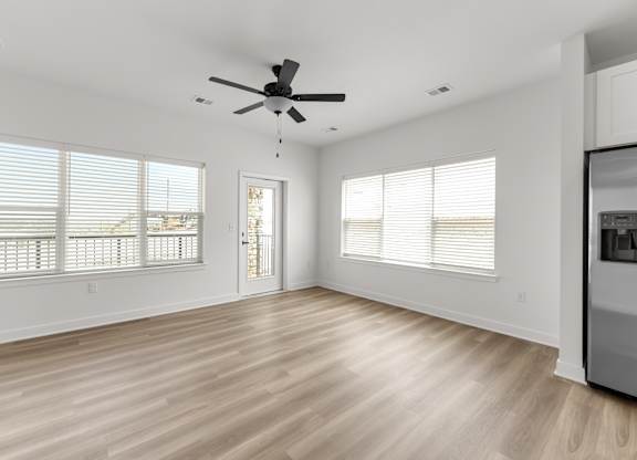 A spacious room with a ceiling fan and wooden flooring.