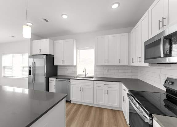 A modern kitchen with white cabinets and stainless steel appliances.