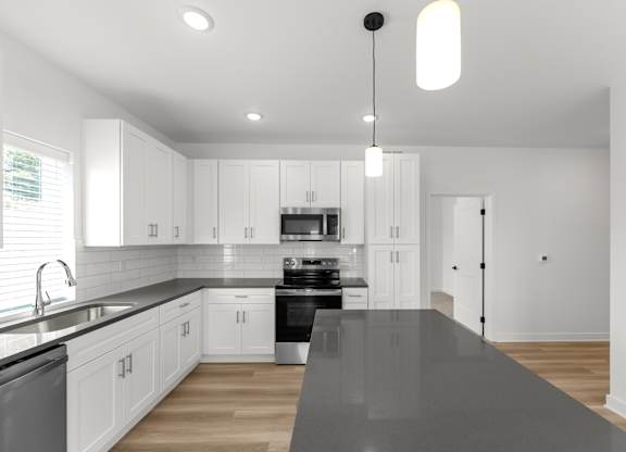 A modern kitchen with white cabinets and a black countertop.
