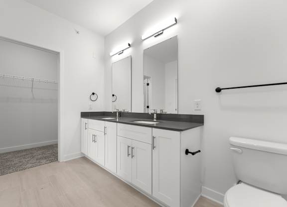 A white bathroom with a toilet, sink, and a mirror.