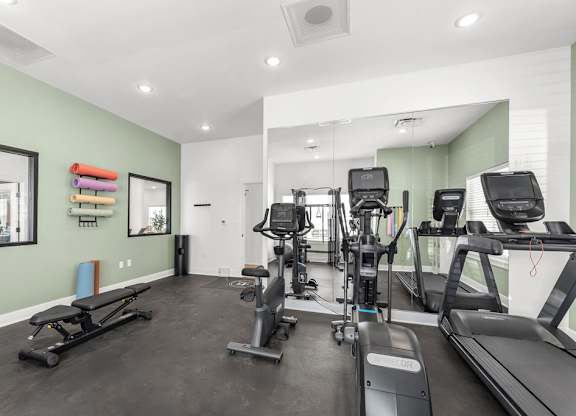A gym with treadmills, exercise bikes, and weights.