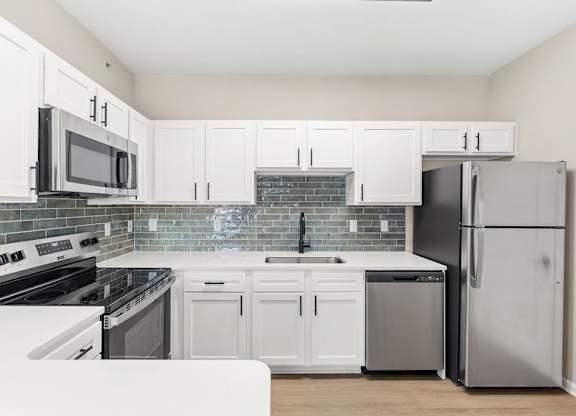 A kitchen with white cabinets and appliances.