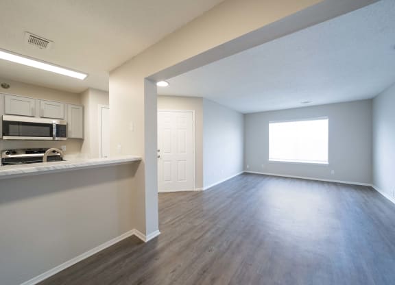an empty living room and kitchen with hard wood flooring