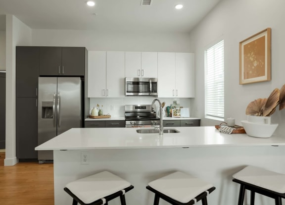 a kitchen with a white counter top and a stainless steel refrigerator
