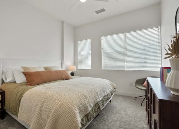 Denver, CO Apartments Near Target - Edera Apartments - Bedroom With Plush Carpet Flooring, a Ceiling Fan, and Large Windows