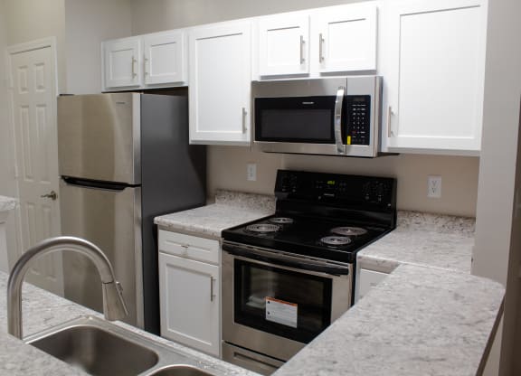 Enclave at Wolfchase Apartments in Cordova Tennessee photo of a kitchen with white cabinets and stainless steel appliances