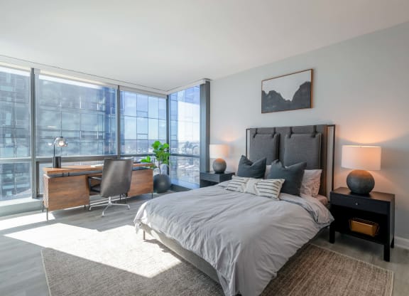 a bedroom with a bed and a desk with a large window