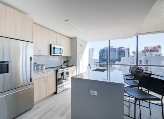 a kitchen with a large island and a stainless steel refrigerator