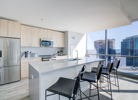 a kitchen with a counter and chairs in front of a window
