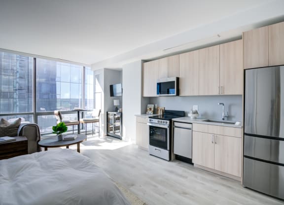 a bedroom with a bed and a kitchen with a refrigerator