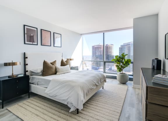 a bedroom with a large window and a bed and a rug