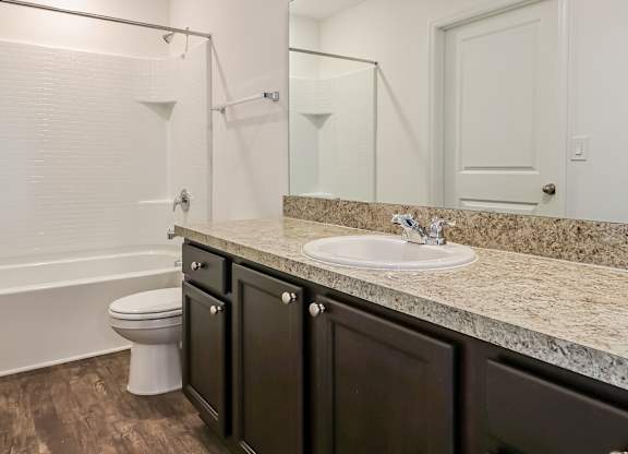 A white toilet sits in a bathroom with a marble countertop.