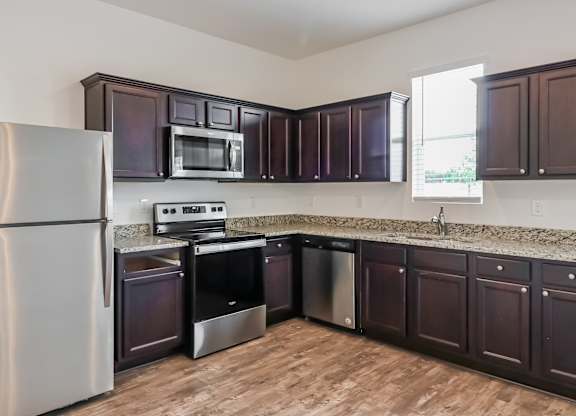 A kitchen with dark brown cabinets and a stainless steel refrigerator.