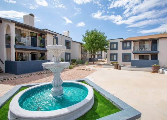 a fountain in the middle of a courtyard with apartments in the background