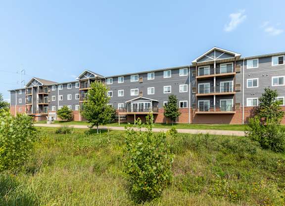 A large apartment complex with multiple balconies and greenery in the foreground.