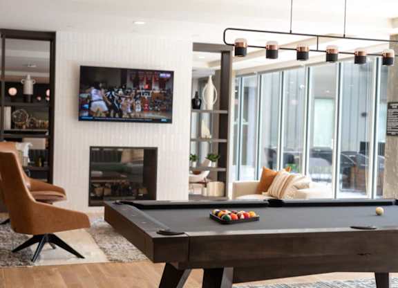 A pool table with a television in the background.