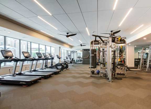A spacious gym with treadmills, elliptical machines, and a weight training area.