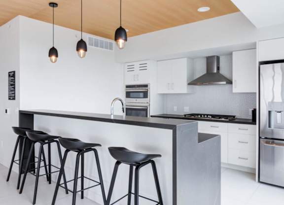 A modern kitchen with a bar area and stools.